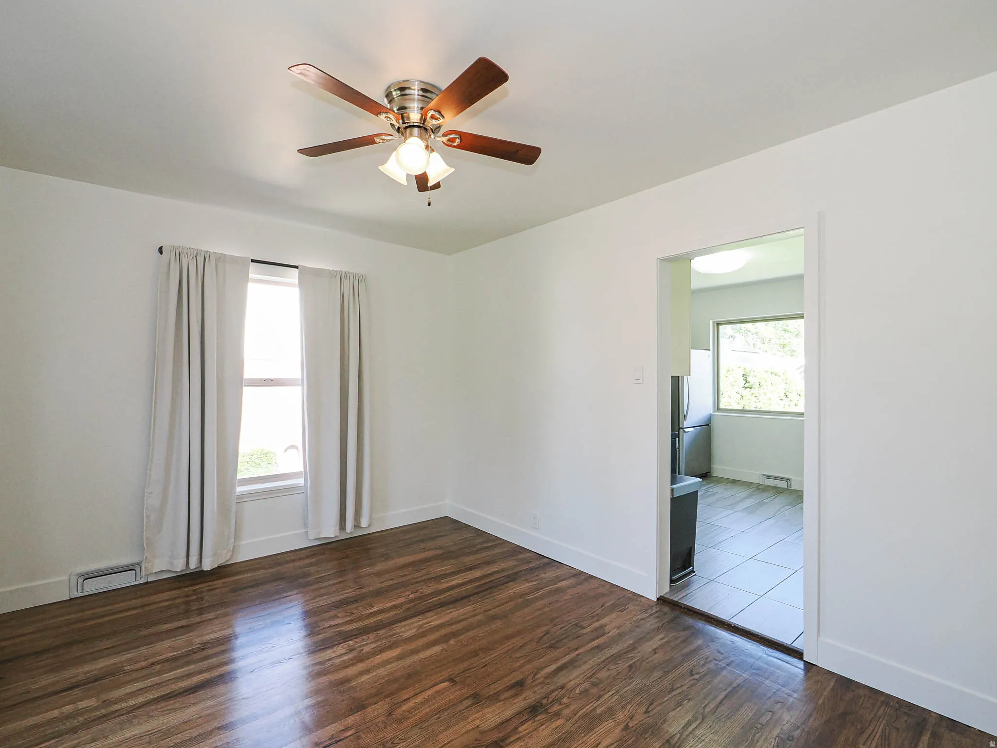 Unfurnished room featuring dark wood-type flooring and ceiling fan