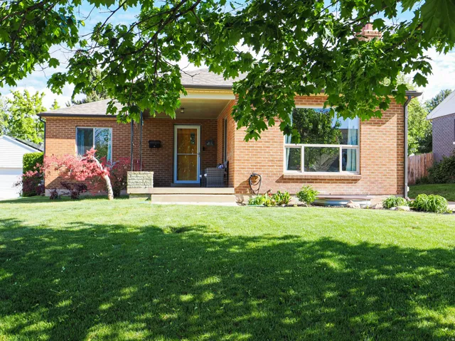 Ranch-style house featuring a porch, brick siding, a front lawn, and roof with shingles