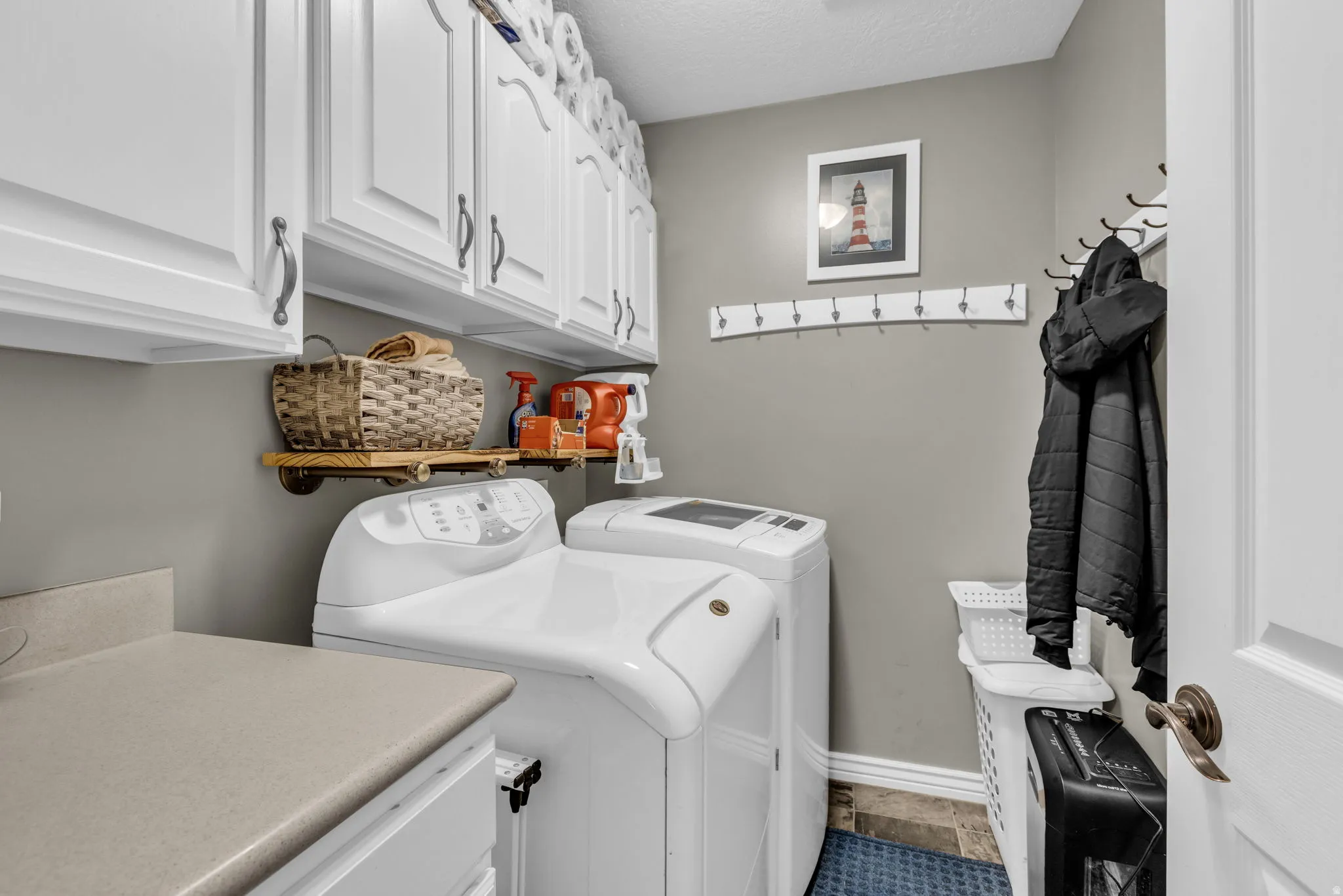Laundry area with a textured ceiling, separate washer and dryer, and cabinet space