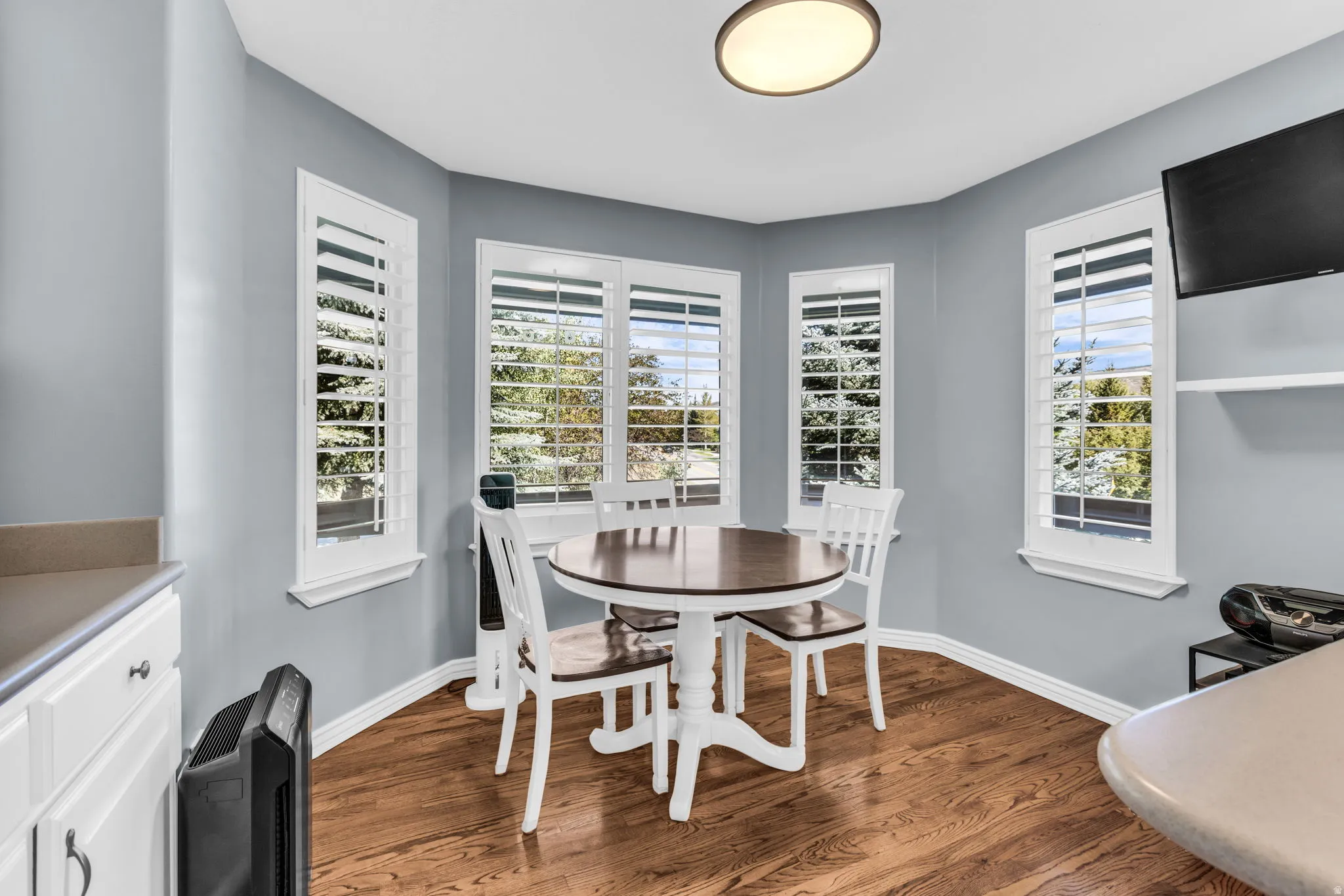 Bay window with plantation shutters, wood-finish flooring, recessed lighting fixture, and light-toned walls