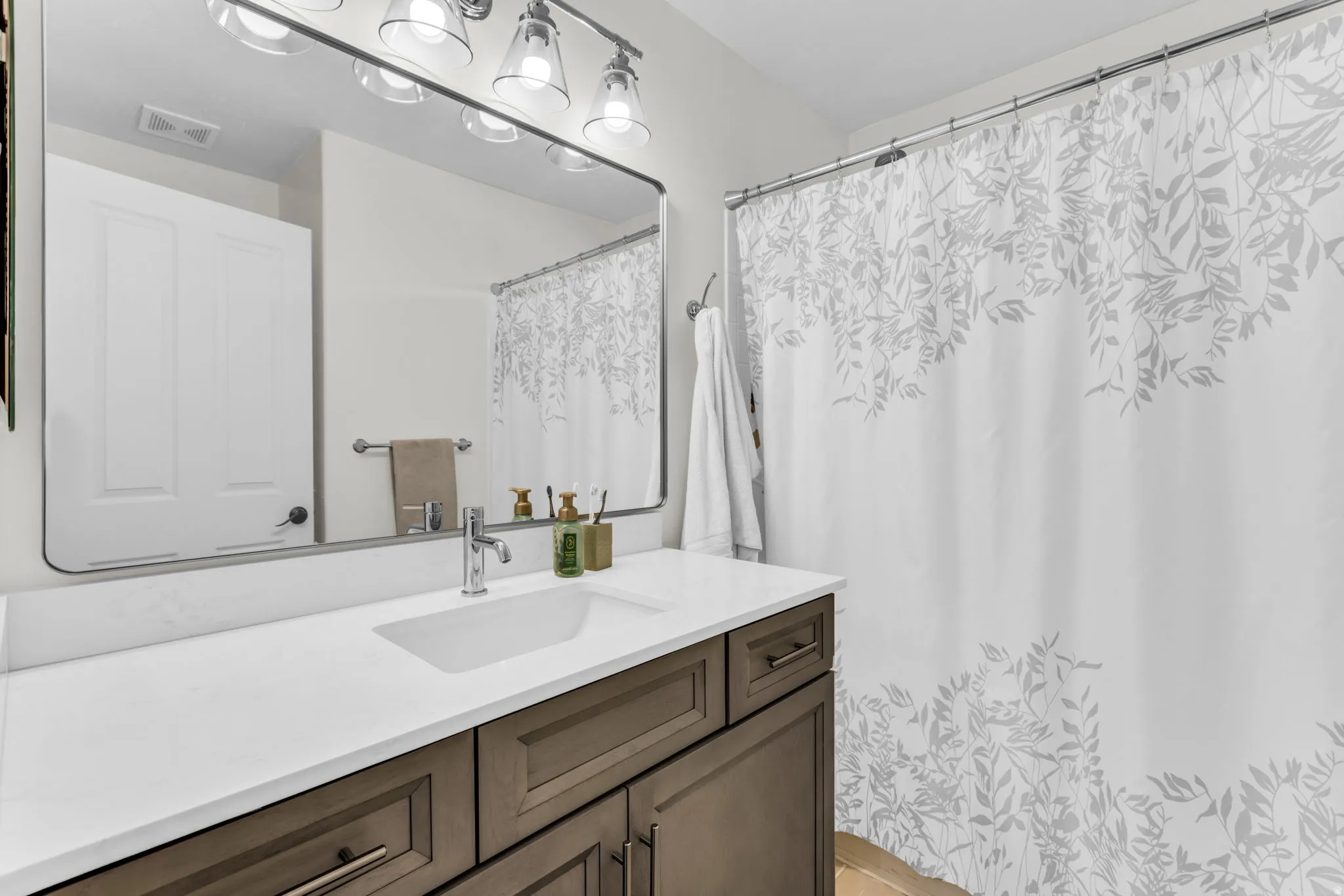 White rectangular undermount sink with chrome faucet, set into a white countertop, with wood-finish cabinetry below