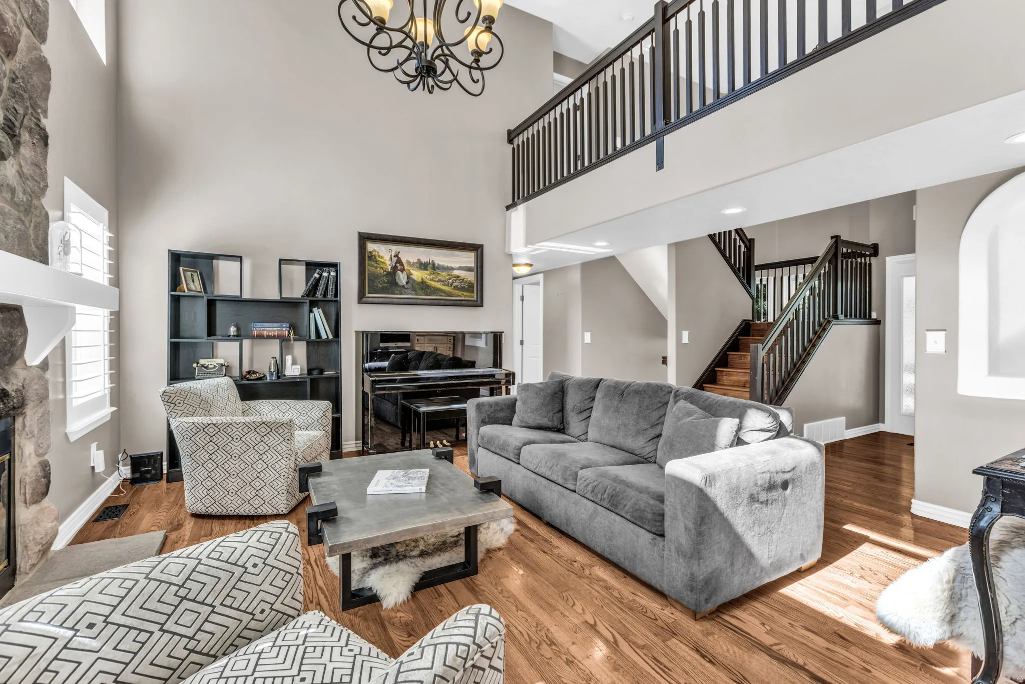 Two-story living room with soaring ceilings, a wrought-iron mezzanine railing, and an ornate pendant chandelier