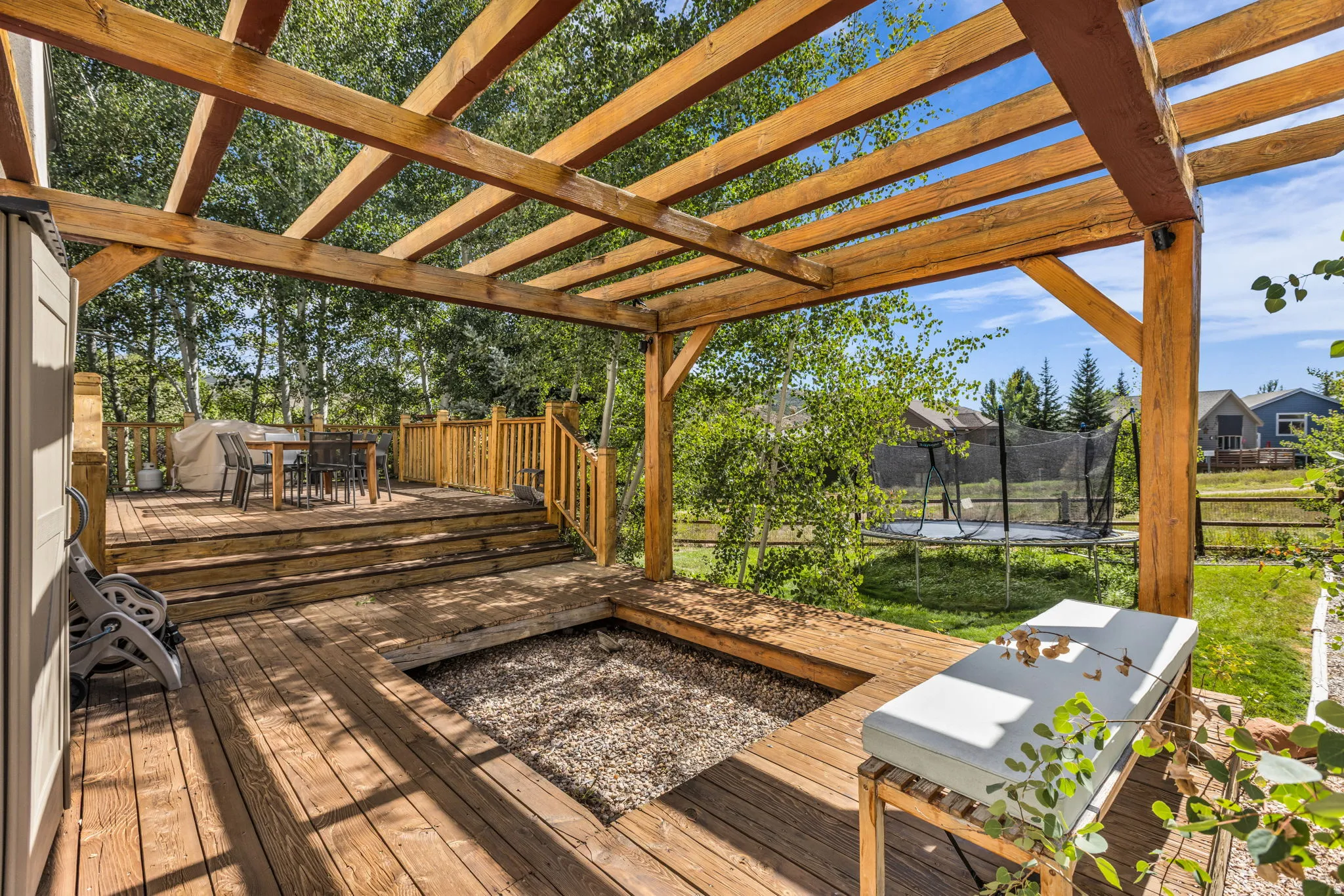 Multi-level wood deck featuring a pergola, built-in gravel pit, and wood railings