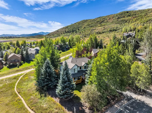 Two-story residence with a multi-level roofline, surrounded by mature trees, situated on a paved street