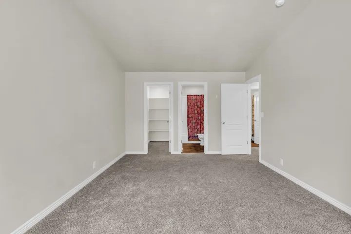 Unfurnished bedroom featuring a walk in closet, connected bathroom, and carpet