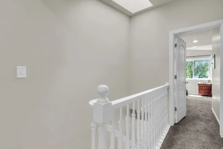 Corridor with a skylight, carpet floors, and an upstairs landing