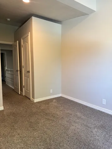 Plush, neutral-toned carpeting extends throughout, complemented by white baseboards and neutral wall finishes