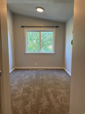 Room featuring a window with white trim, a black curtain rod, and a flush-mount ceiling light