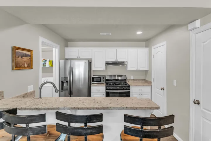 Kitchen with stainless steel appliances, a breakfast bar area, a peninsula, white cabinets, and recessed lighting