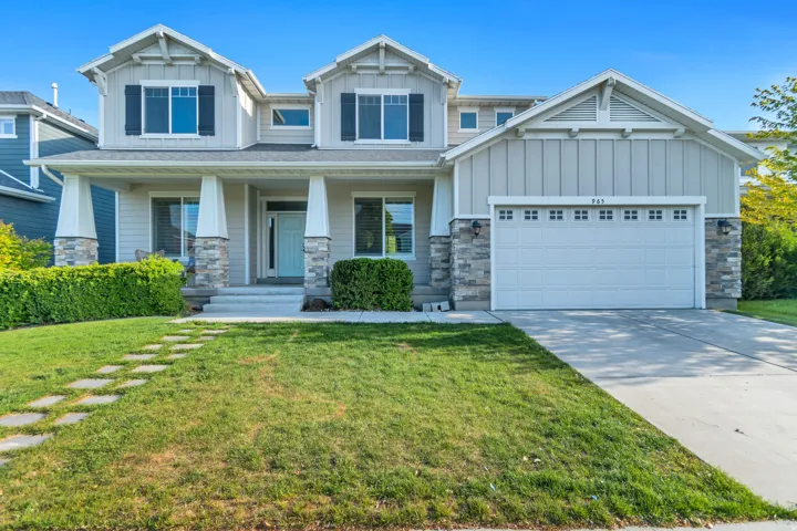 Craftsman house featuring board and batten siding, a porch, stone siding, and a front yard