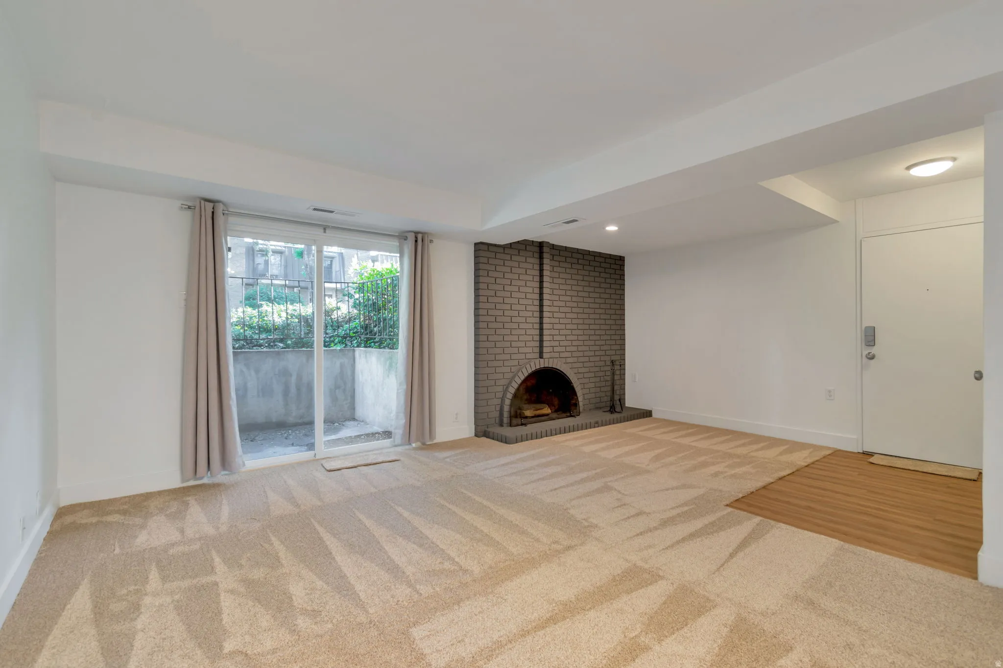Unfurnished living room with light carpet and a fireplace