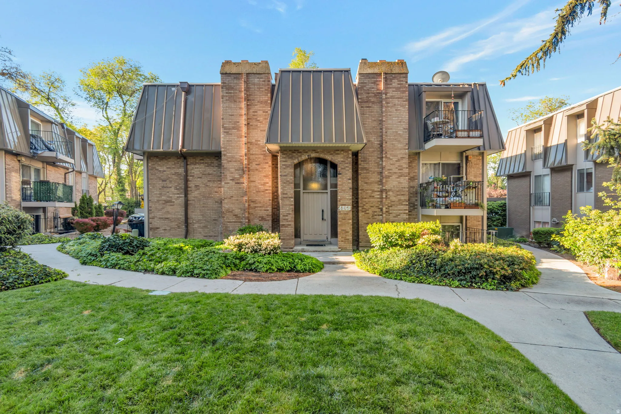 View of front of property with a chimney, brick siding, a front yard, and a standing seam roof