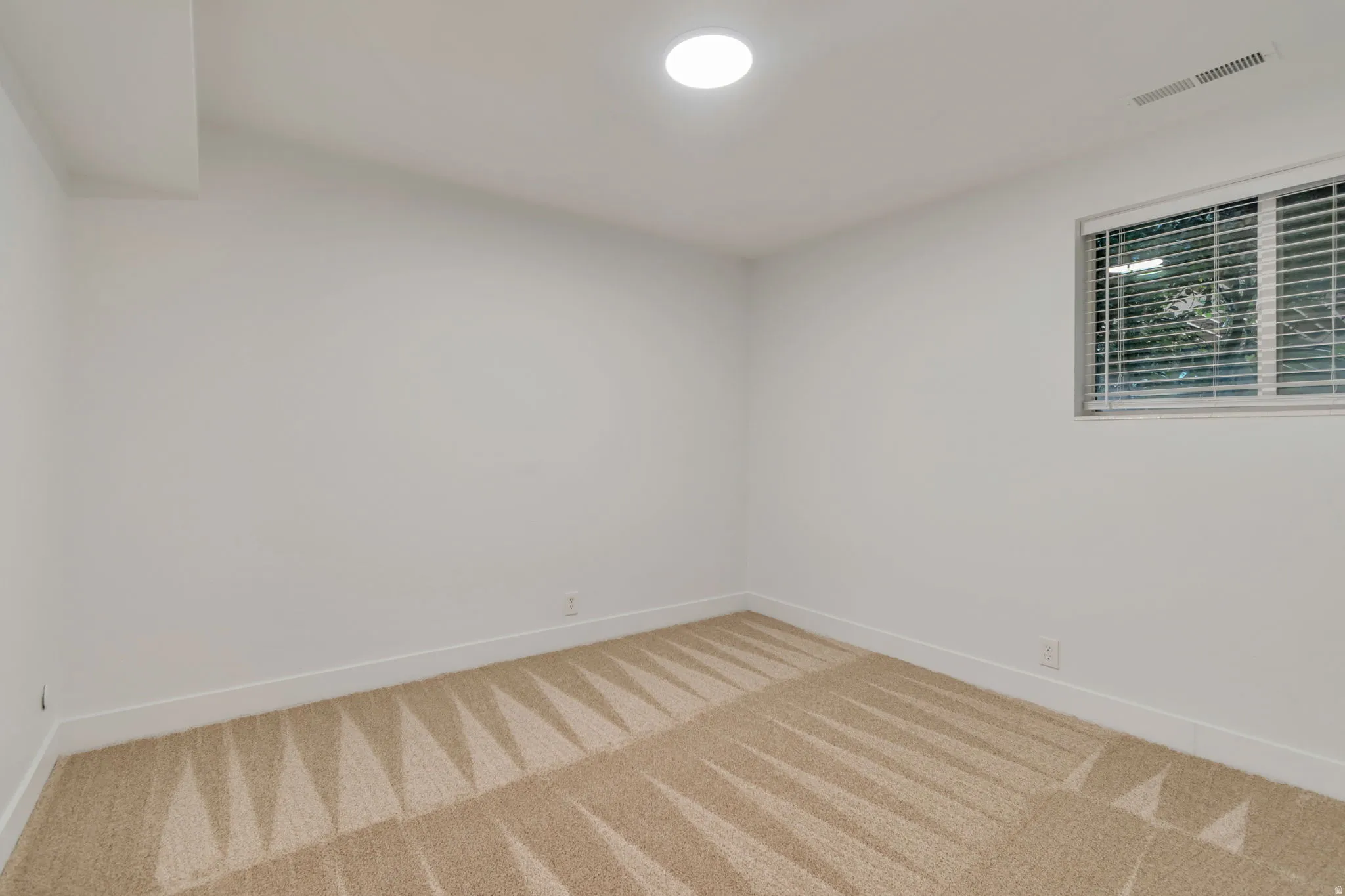 Spare room with baseboards and light colored carpet