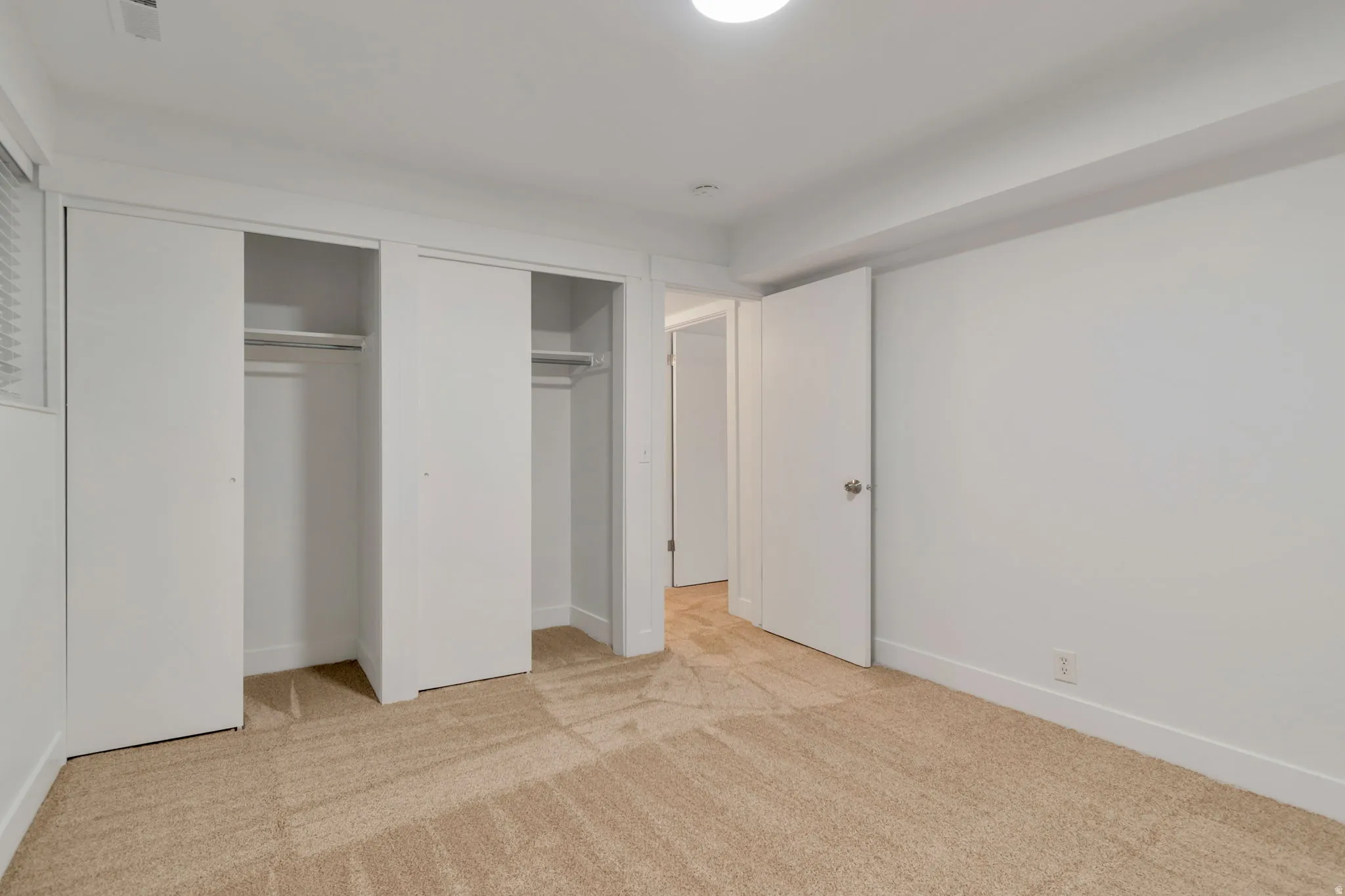 Unfurnished bedroom with two closets and light carpet