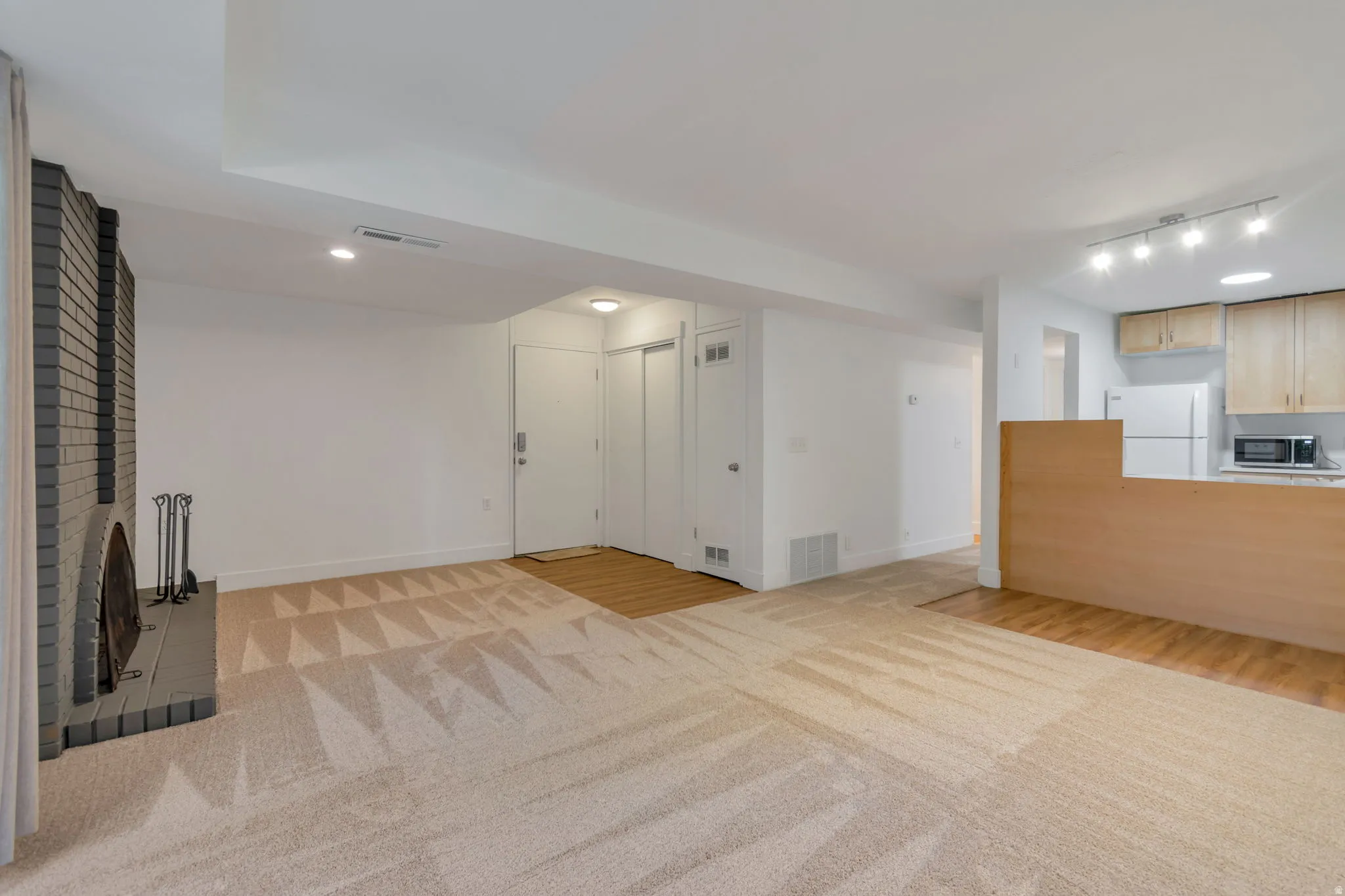 Unfurnished living room with light wood-style floors and light carpet