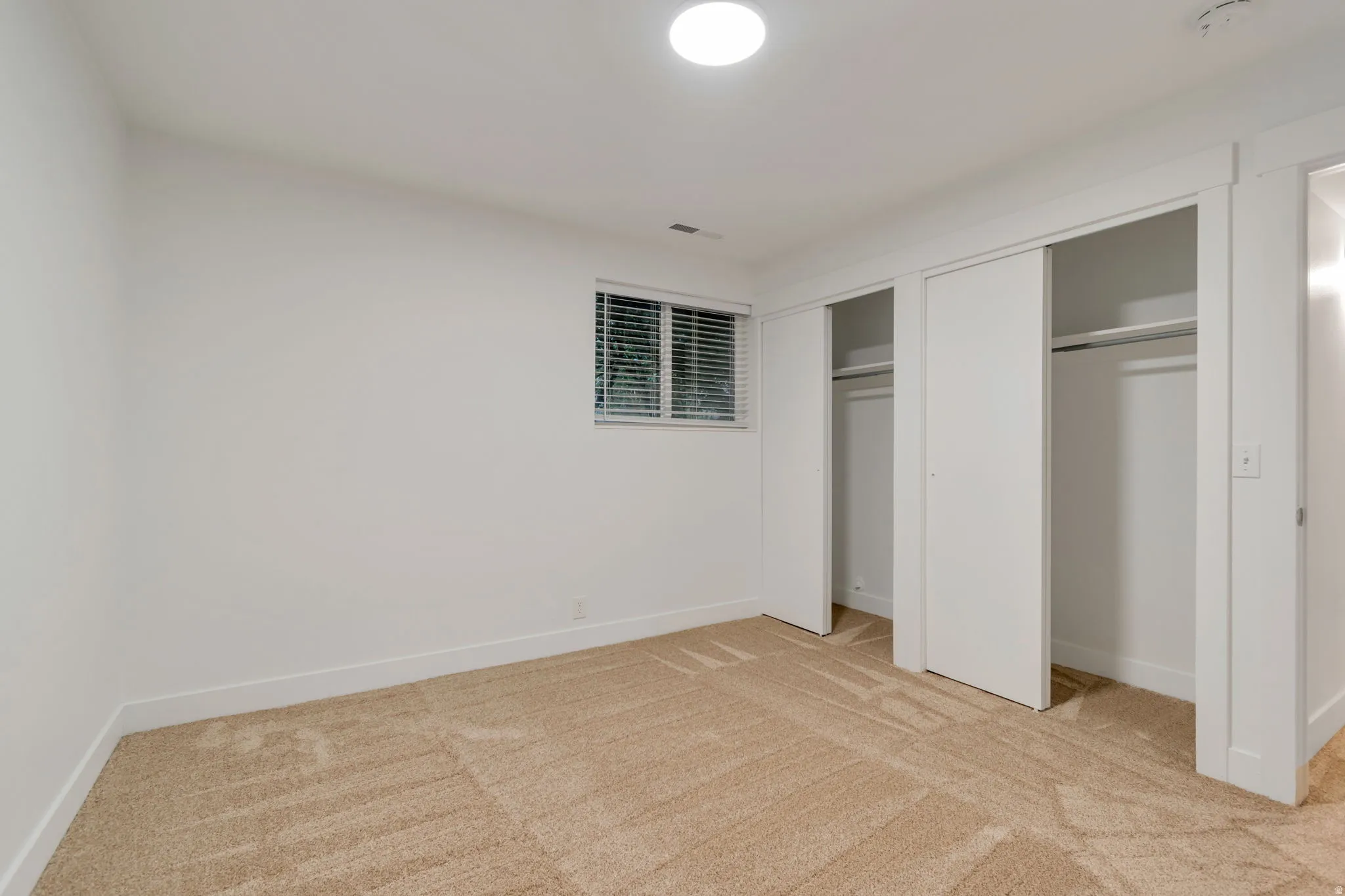 Unfurnished bedroom with multiple closets and light colored carpet