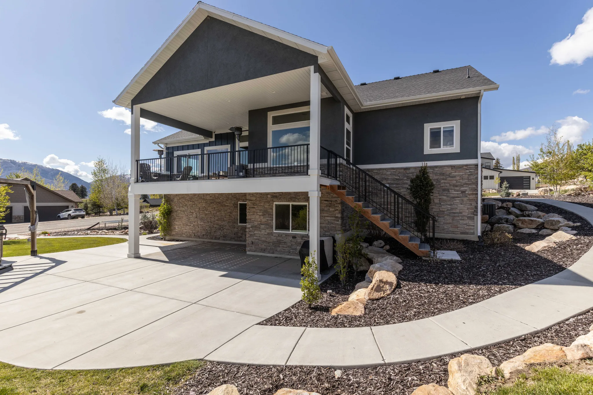 Rear view of property with stone siding, stucco siding, a mountain view, and a balcony