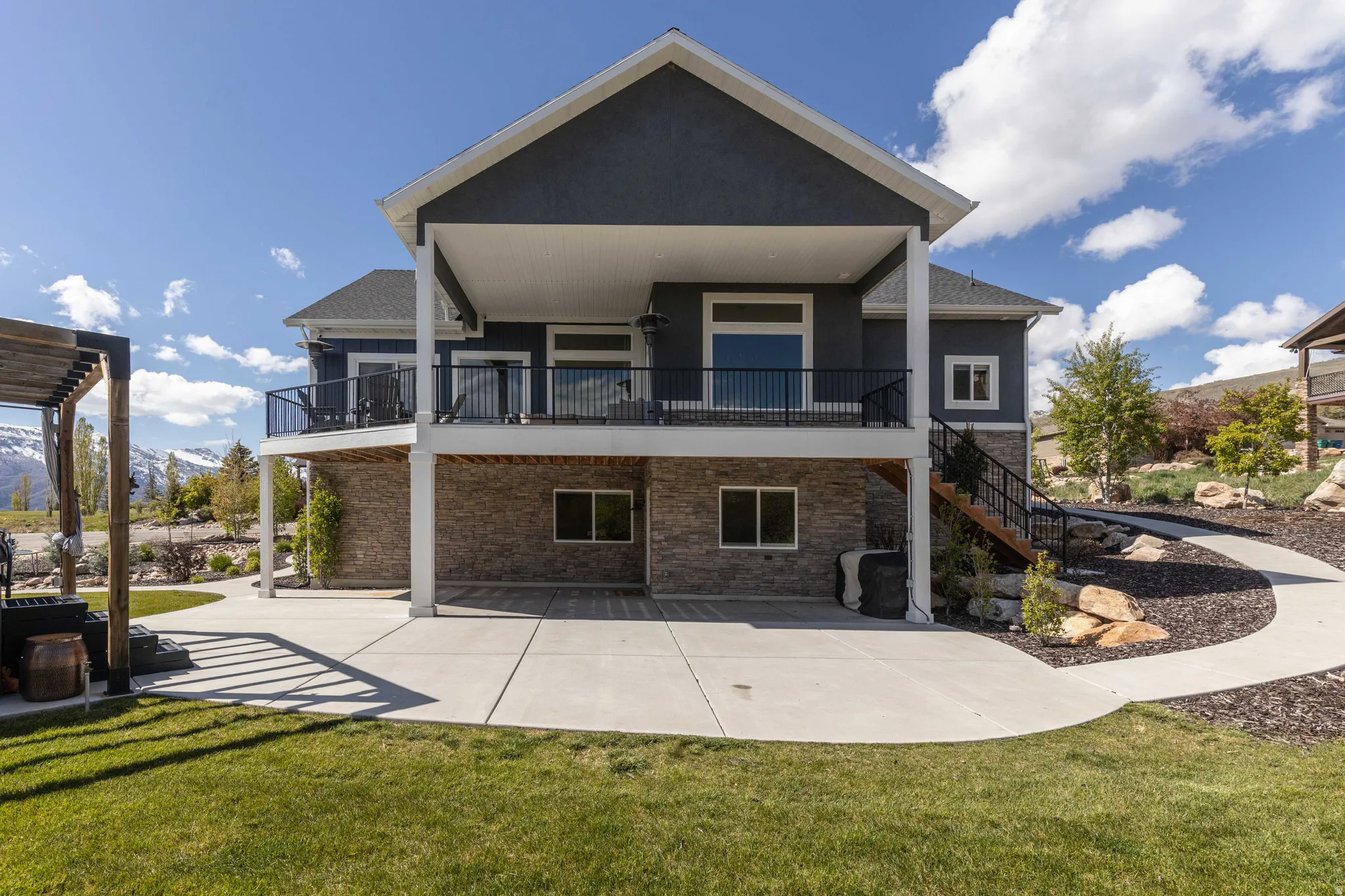 Back of property featuring a balcony, a lawn, a mountain view, and stucco siding