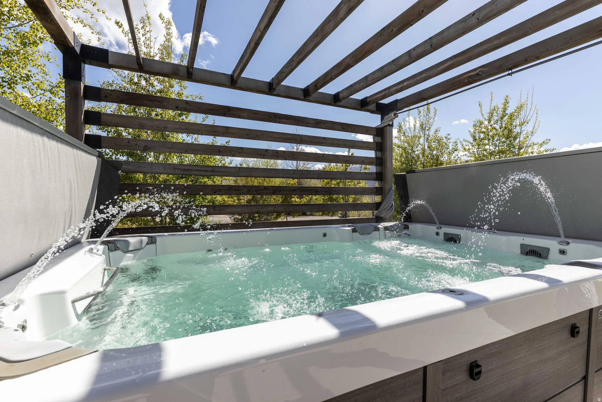 View of swimming pool with a hot tub and a pergola