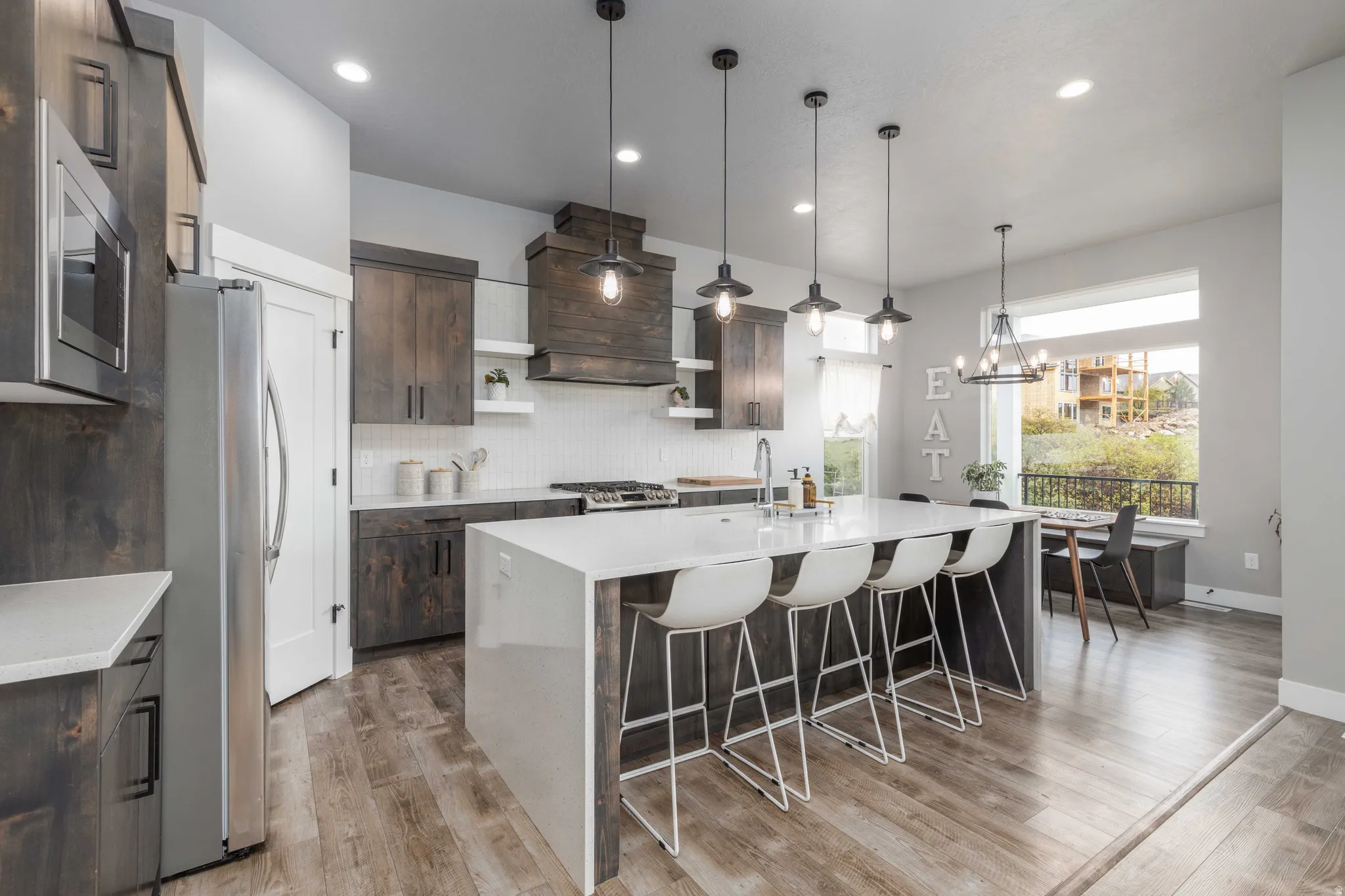 Kitchen with open shelves, light stone countertops, dark wood finish cabinetry, stainless steel appliances, and a large island