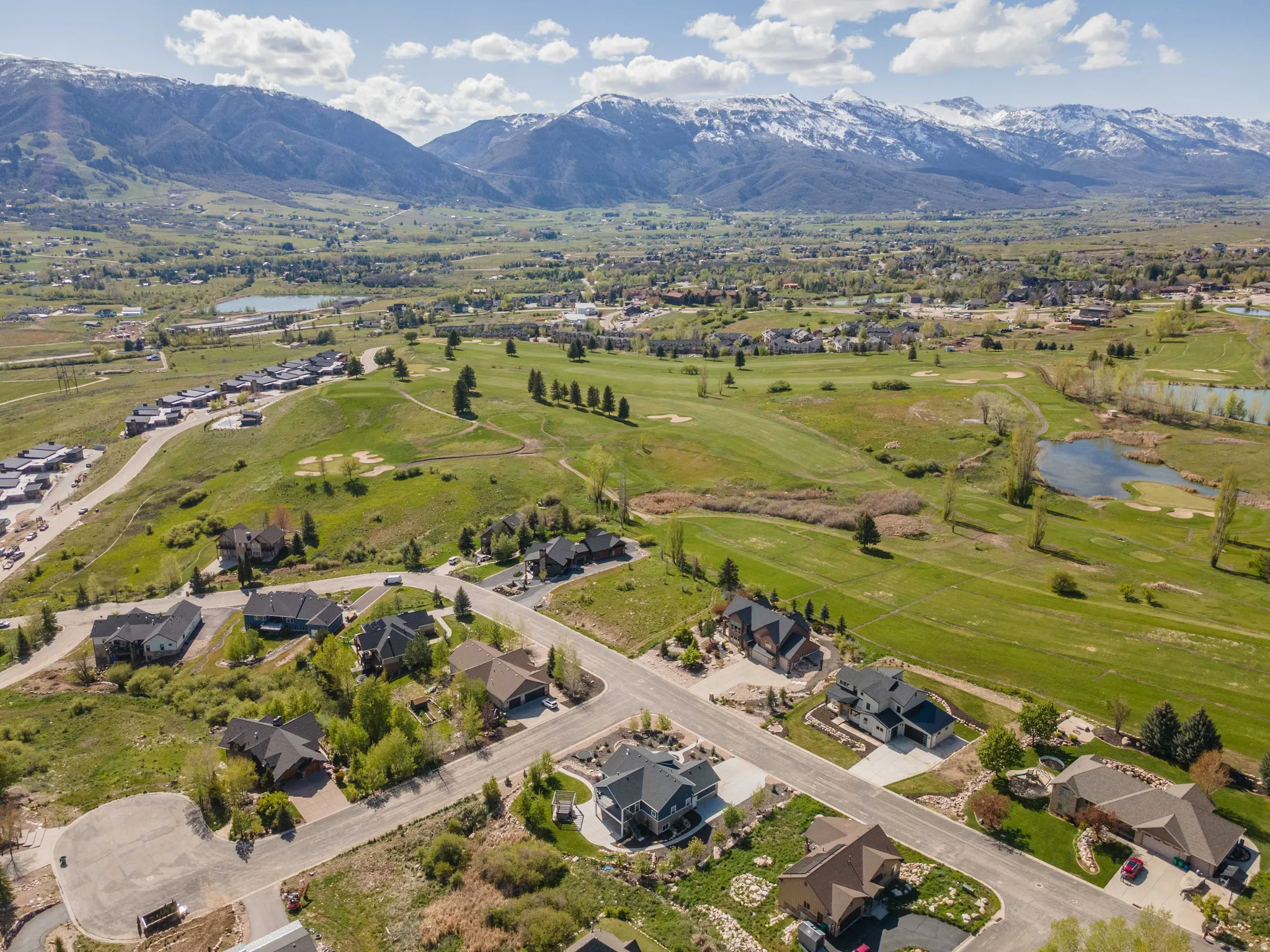 Aerial perspective of suburban area with a water and mountain view and a golf club