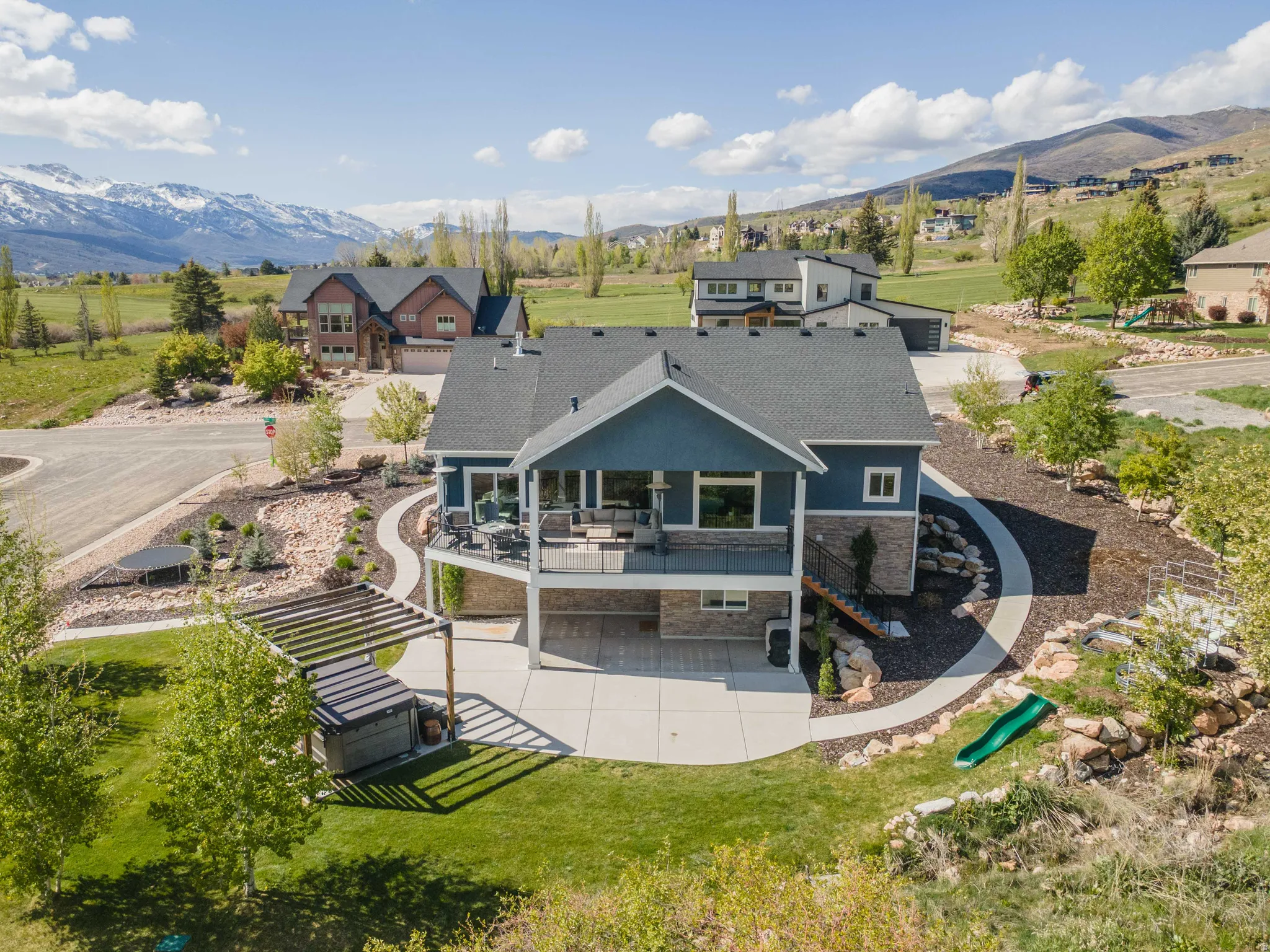 Rear view of house featuring stone siding, a patio, a balcony, and a mountain view