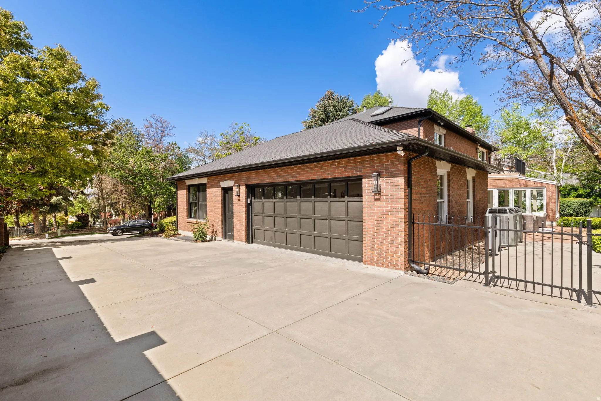 View of property exterior with concrete driveway, brick siding, a gate, a garage, and a chimney