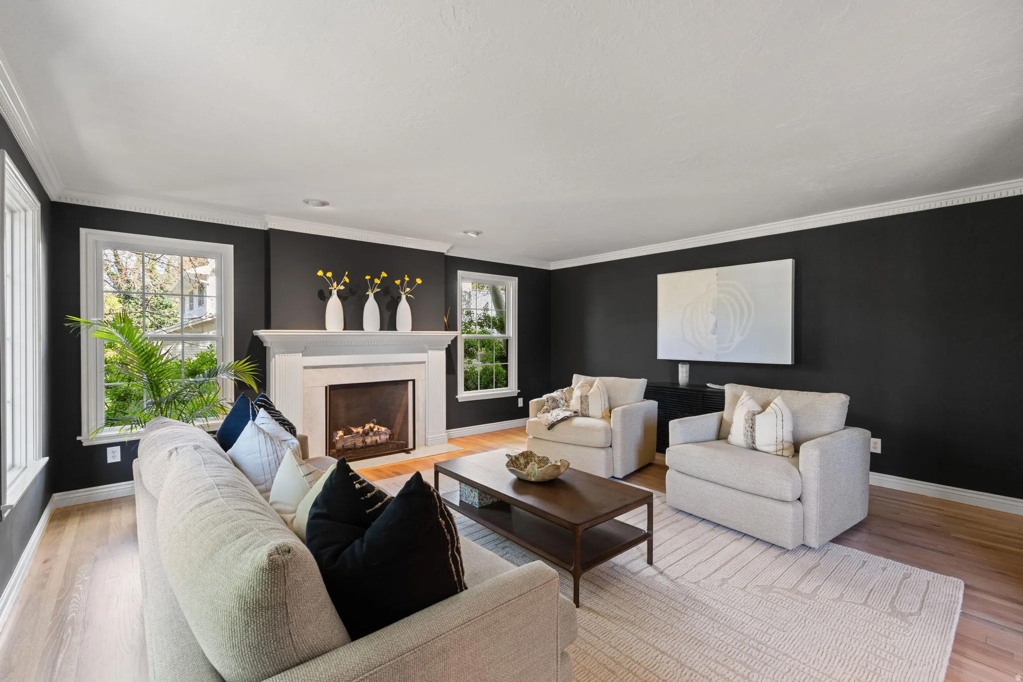 Living area featuring a high end fireplace, light wood-type flooring, and ornamental molding