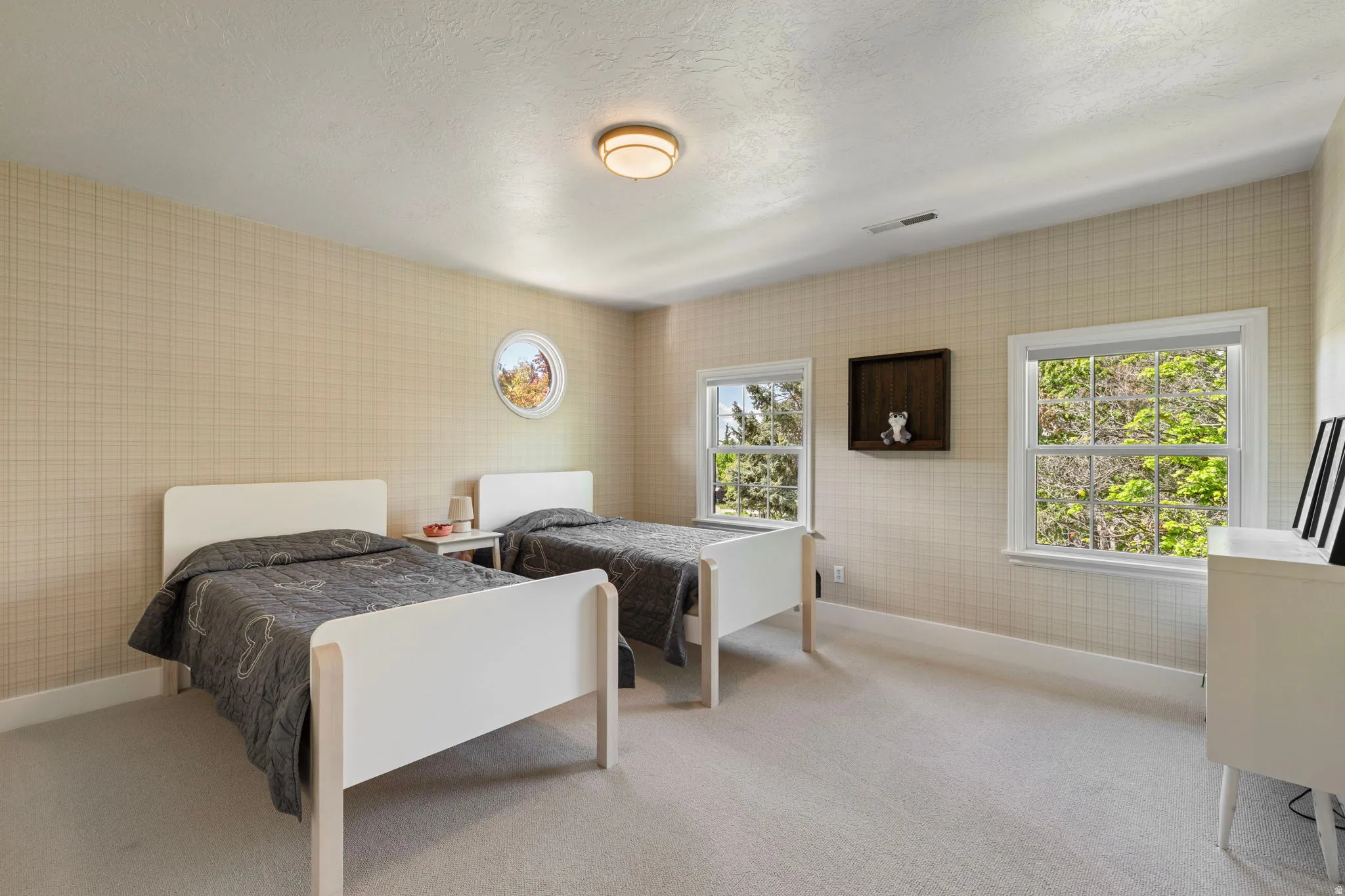 Bedroom with wallpapered walls, light colored carpet, and a textured ceiling