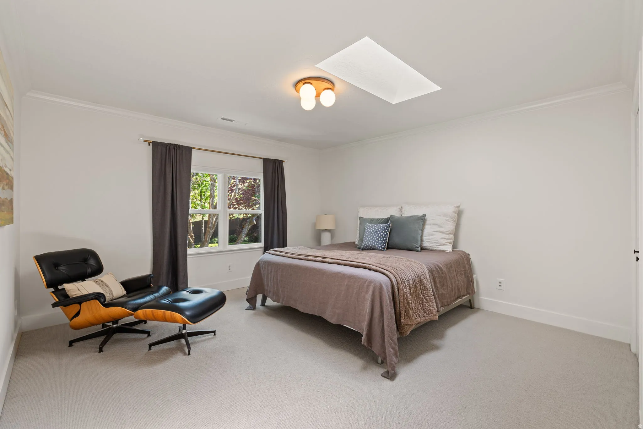 Bedroom featuring a skylight, light carpet, and ornamental molding