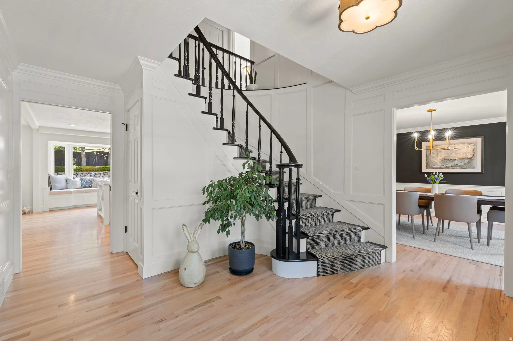 Stairway with a decorative wall, wood finished floors, and ornamental molding