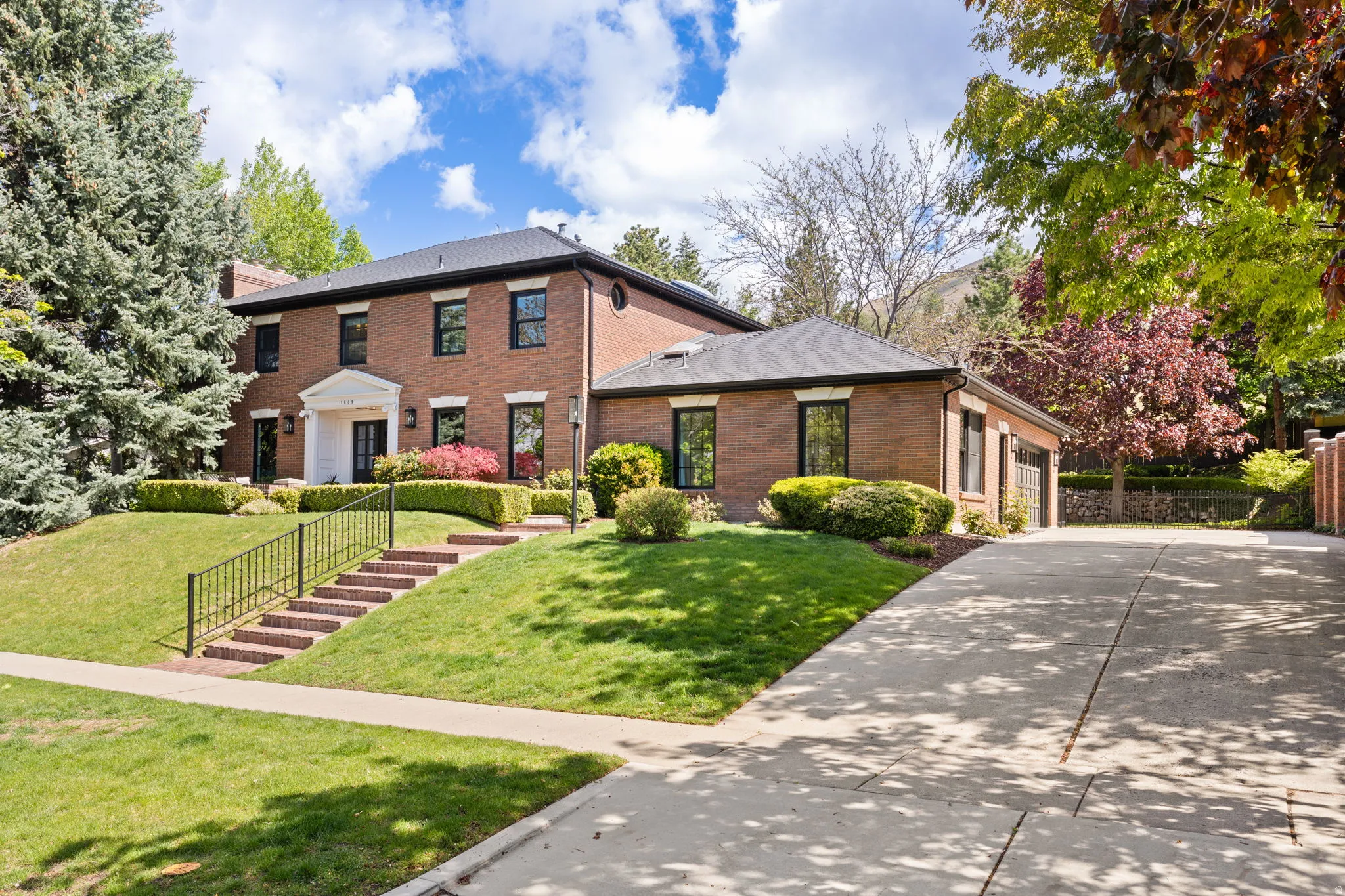 Colonial house with brick siding, an attached garage, and driveway