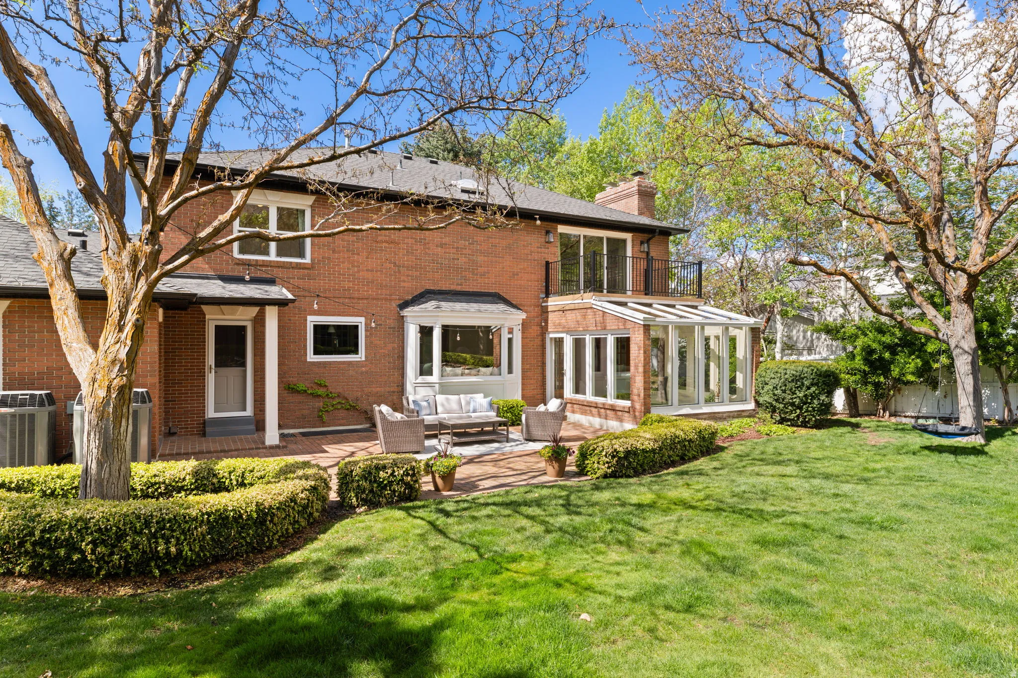 Back of property featuring a sunroom, an outdoor living space, a yard, and brick siding