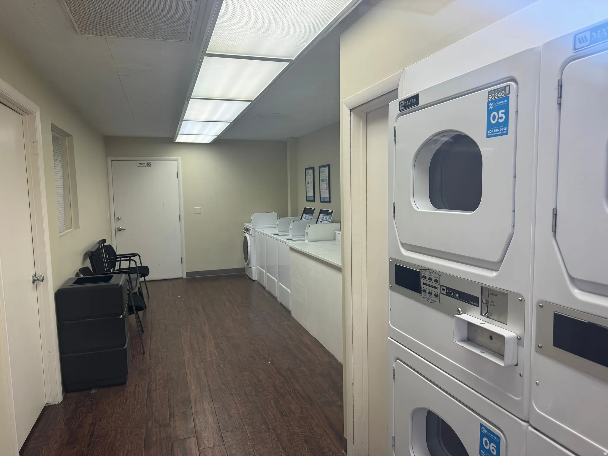 Community laundry facility featuring multiple stacked white washers and dryers