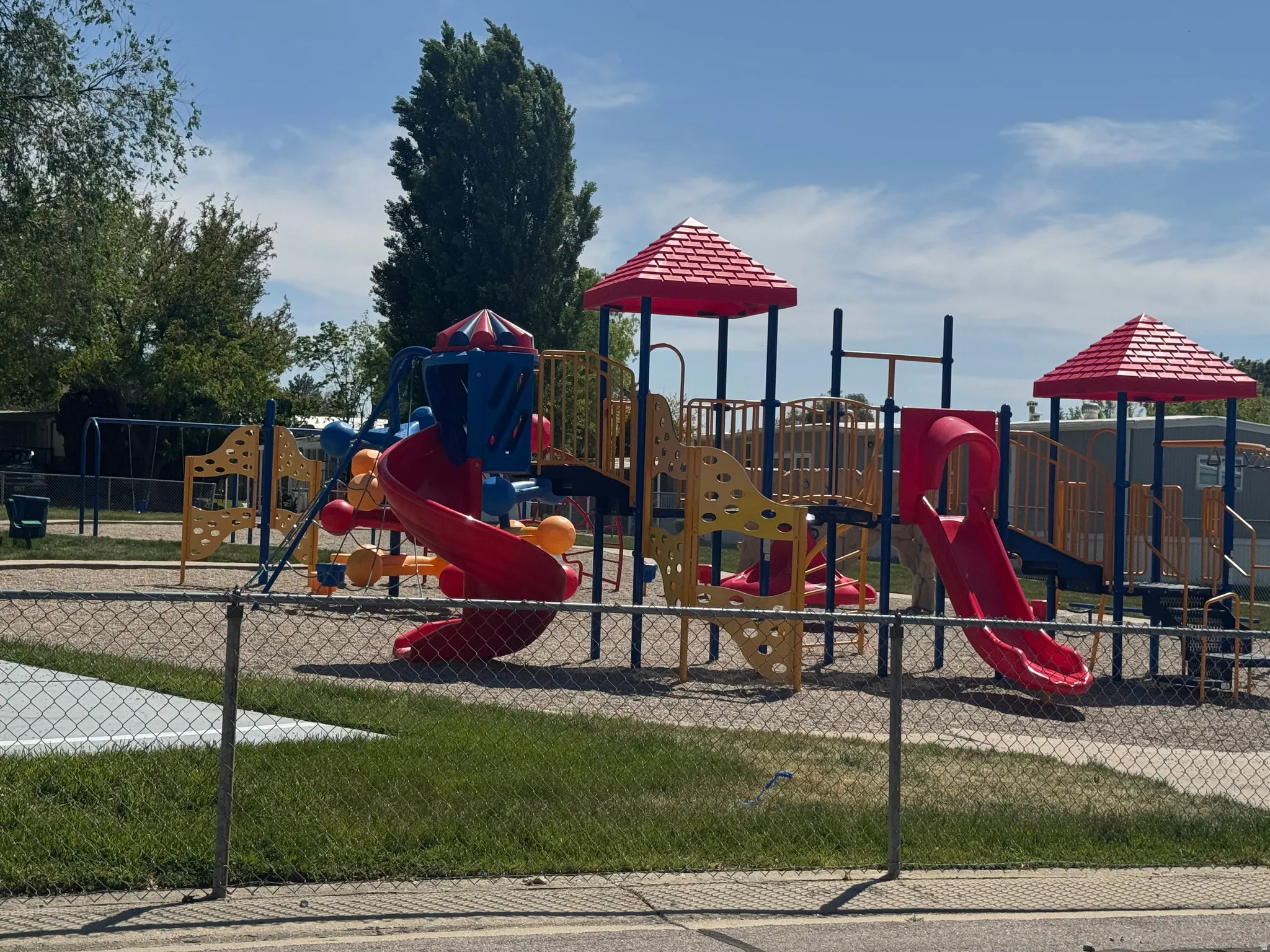 Playground structure featuring multiple slides, climbing elements, and overhead shade canopies