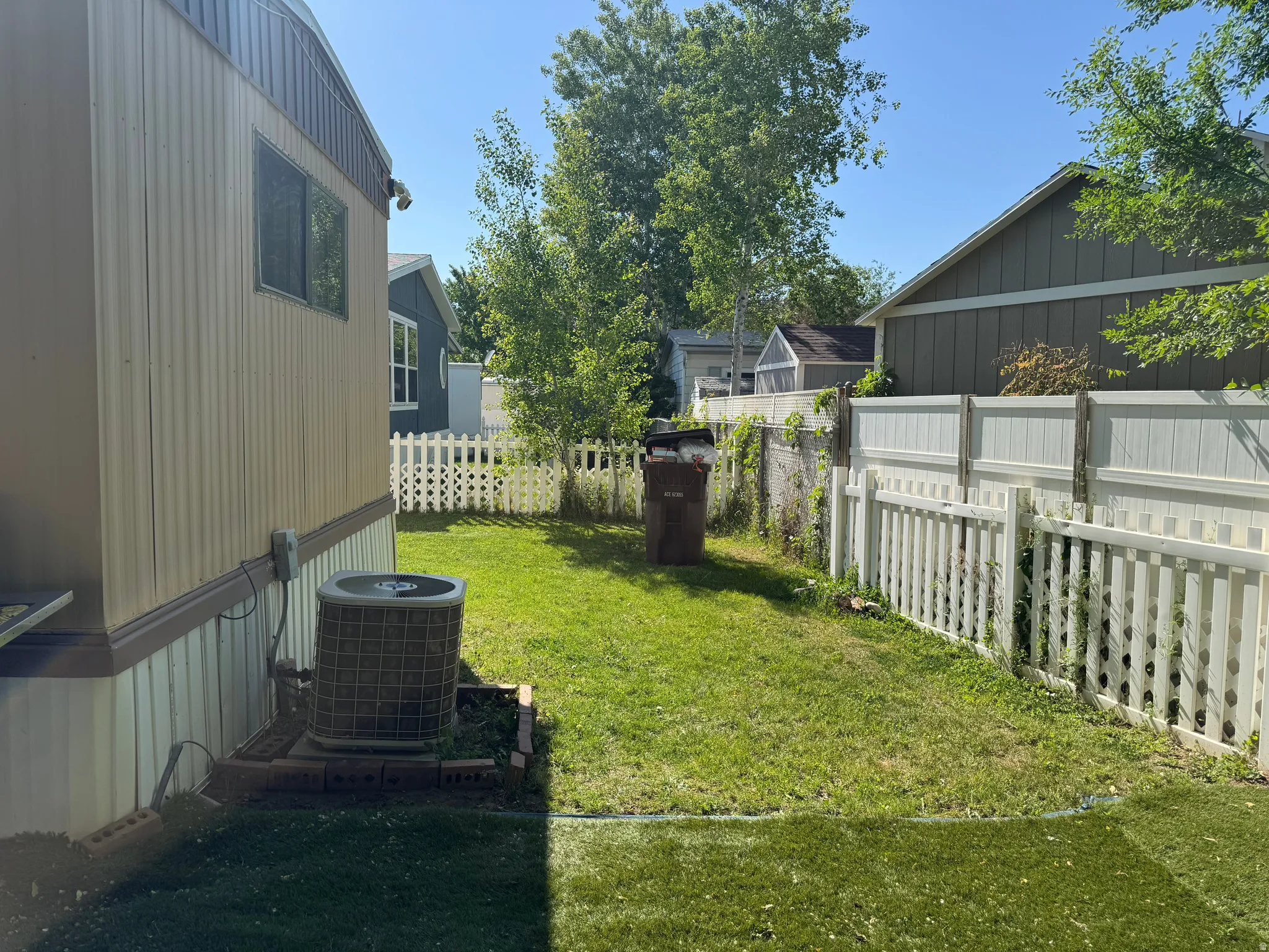 Expansive grassy yard area featuring a combination of picket and privacy fencing