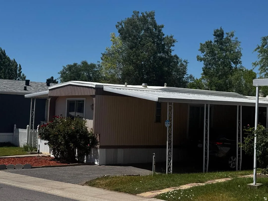 Single-story exterior with a covered carport, paved driveway, and mature landscaping