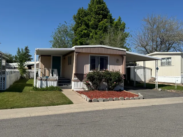 Exterior featuring a covered front entry, a single-car carport, and a front yard with mature landscaping
