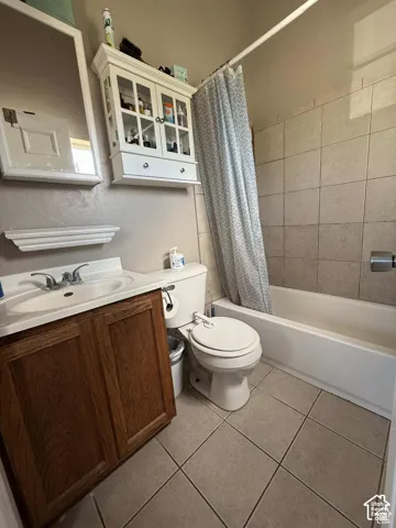 Bathroom featuring vanity, shower / bath combination with curtain, and light tile patterned floors