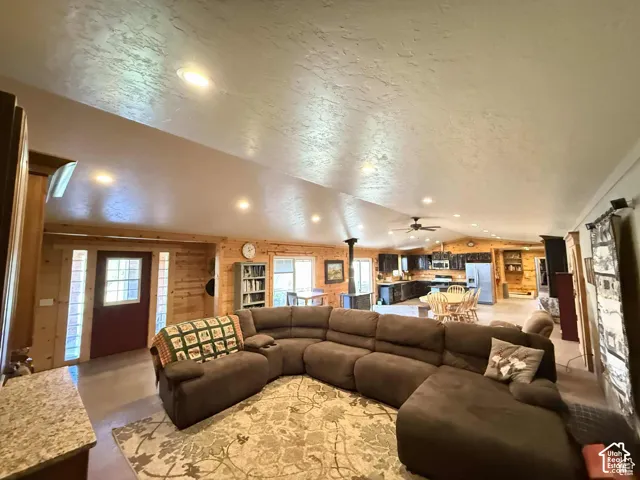 Living area featuring recessed lighting, a ceiling fan, wooden walls, and plenty of natural light