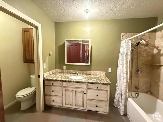 Full bath with vanity, a textured ceiling, and shower / bathtub combination with curtain