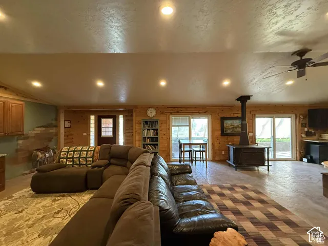 Living room featuring a wood stove, ceiling fan, recessed lighting, a textured ceiling, and concrete floors