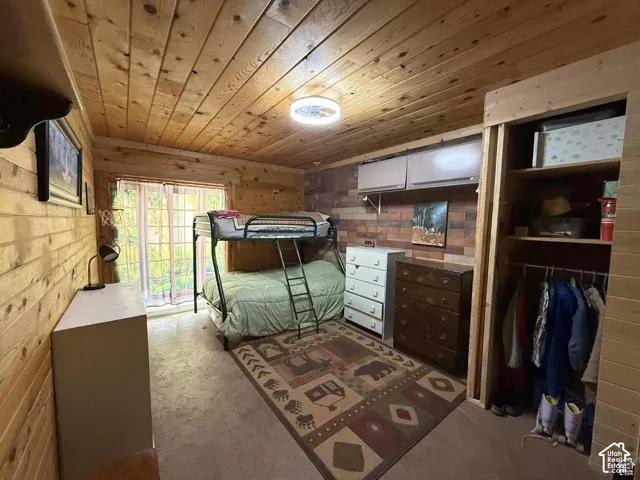 Bedroom with concrete flooring, wood walls, and wooden ceiling
