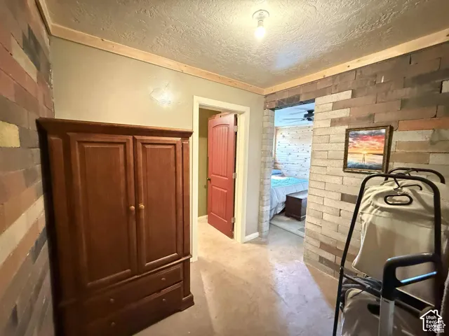Bedroom featuring a textured ceiling, concrete flooring, and brick wall