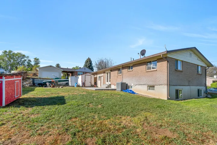 Rear view of property featuring a patio area, brick siding, and a storage shed