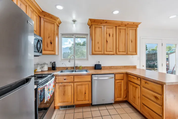 Kitchen featuring stainless steel appliances, a peninsula, light tile patterned flooring, light countertops, and recessed lighting