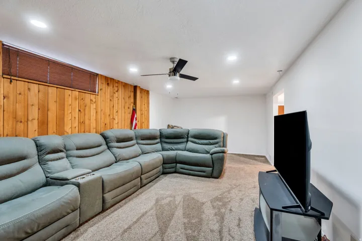 Carpeted cinema with a ceiling fan, wooden walls, and recessed lighting