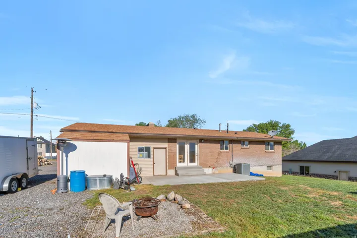 Back of house featuring a patio area, an outdoor fire pit, a lawn, entry steps, and brick siding