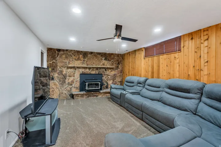 Living area featuring wooden walls, a ceiling fan, carpet, and recessed lighting