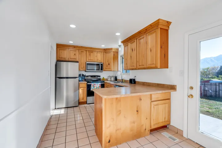 Kitchen featuring a peninsula, stainless steel appliances, light tile patterned floors, light countertops, and recessed lighting
